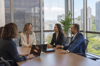 a group of people sitting around a table with laptops a group of people sitting around a table with laptops
